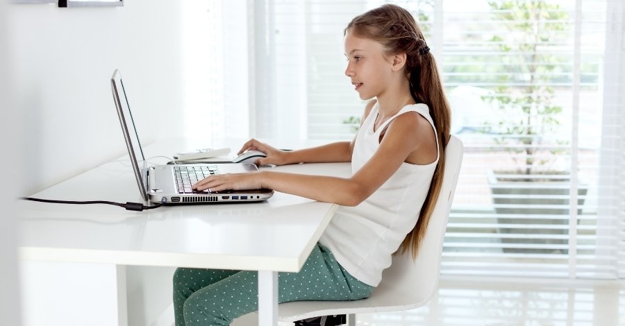tween girl sitting at a desk working on her laptop