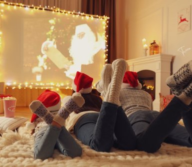 a family lying on the floor watching a christmas movie on a big projector screen