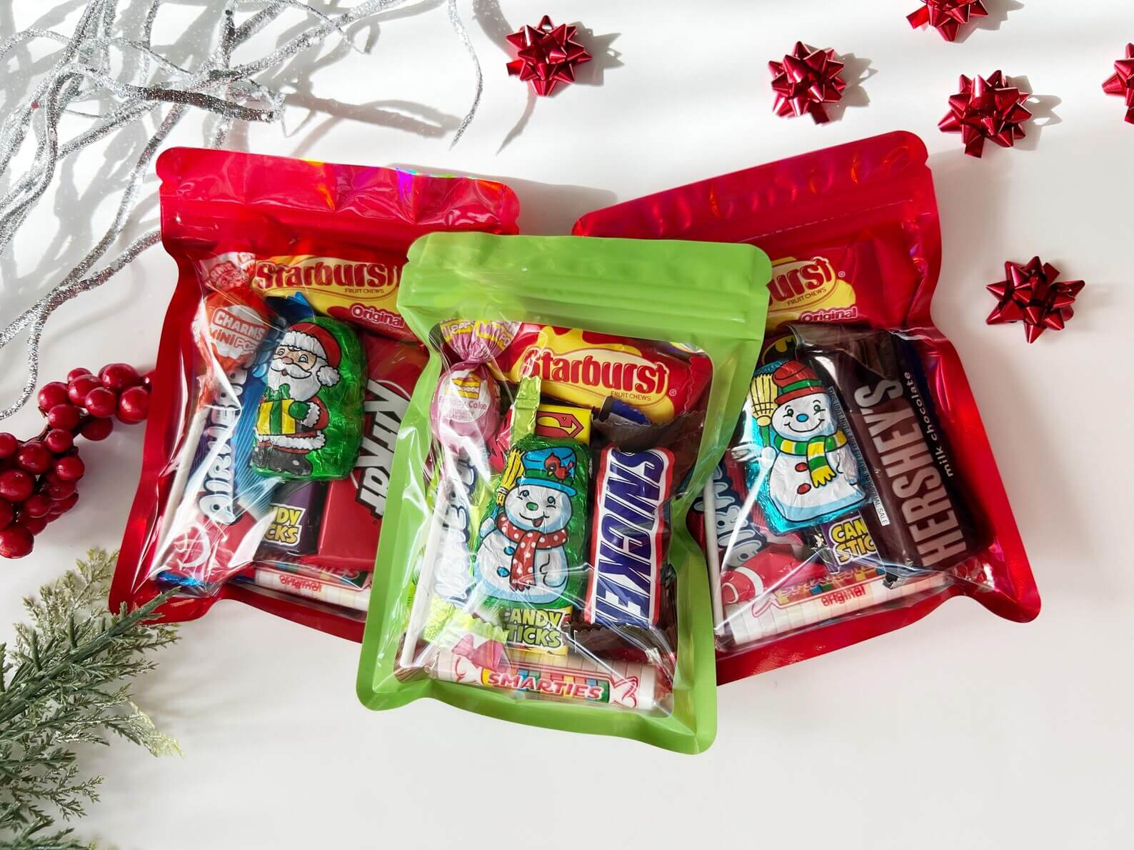Red and green resealable pouches filled with assorted Christmas candies including chocolates, fruit chews, and lollipops, ideal for Christmas Eve Box ideas for tweens.