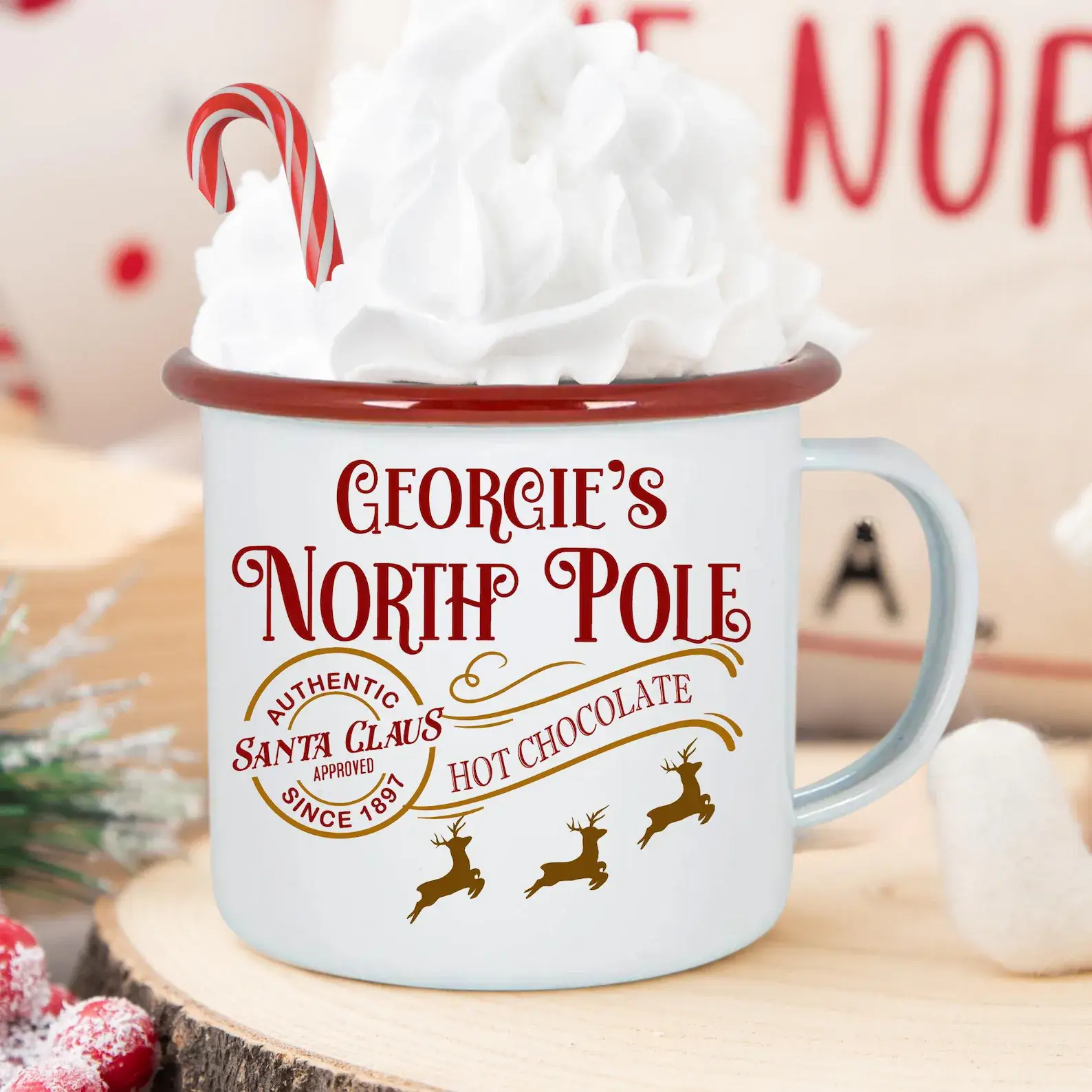 White enamel campfire mug topped with whipped cream and a candy cane, featuring leaping reindeer illustrations, perfect for Christmas Eve Box ideas for tweens.