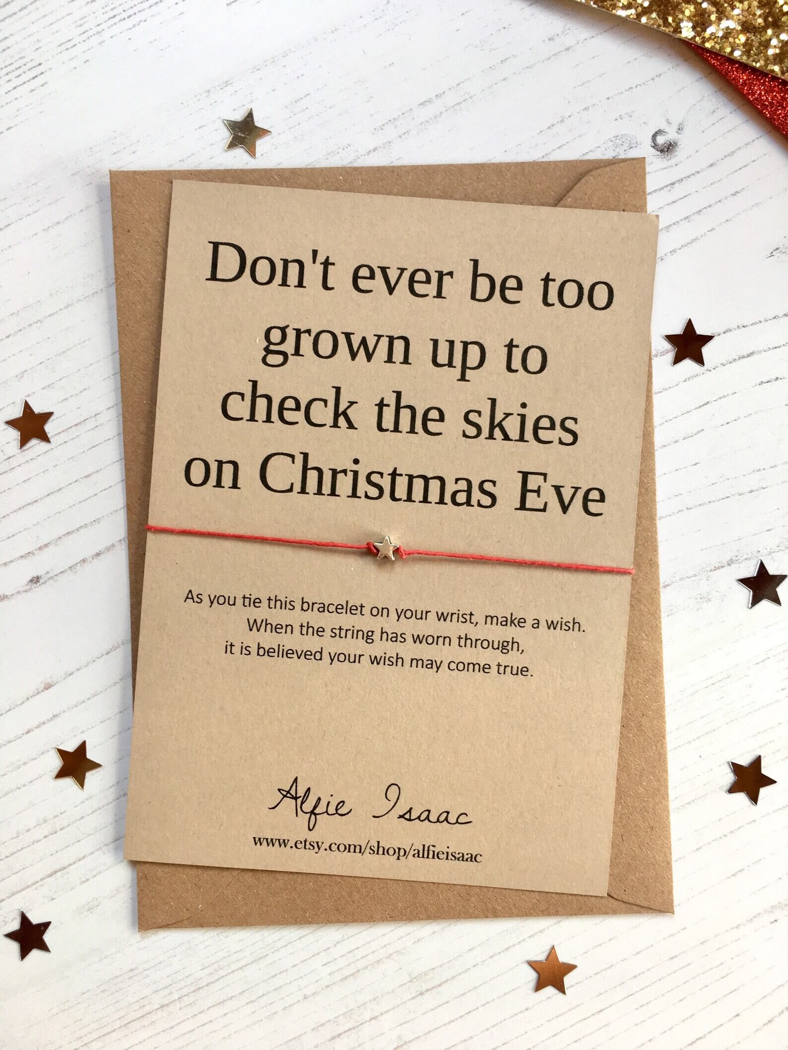 Christmas Eve wish bracelet with a red string and star charm on a kraft card reading "Don't ever be too grown up to check the skies," a sweet keepsake for a tween's Christmas Eve box.